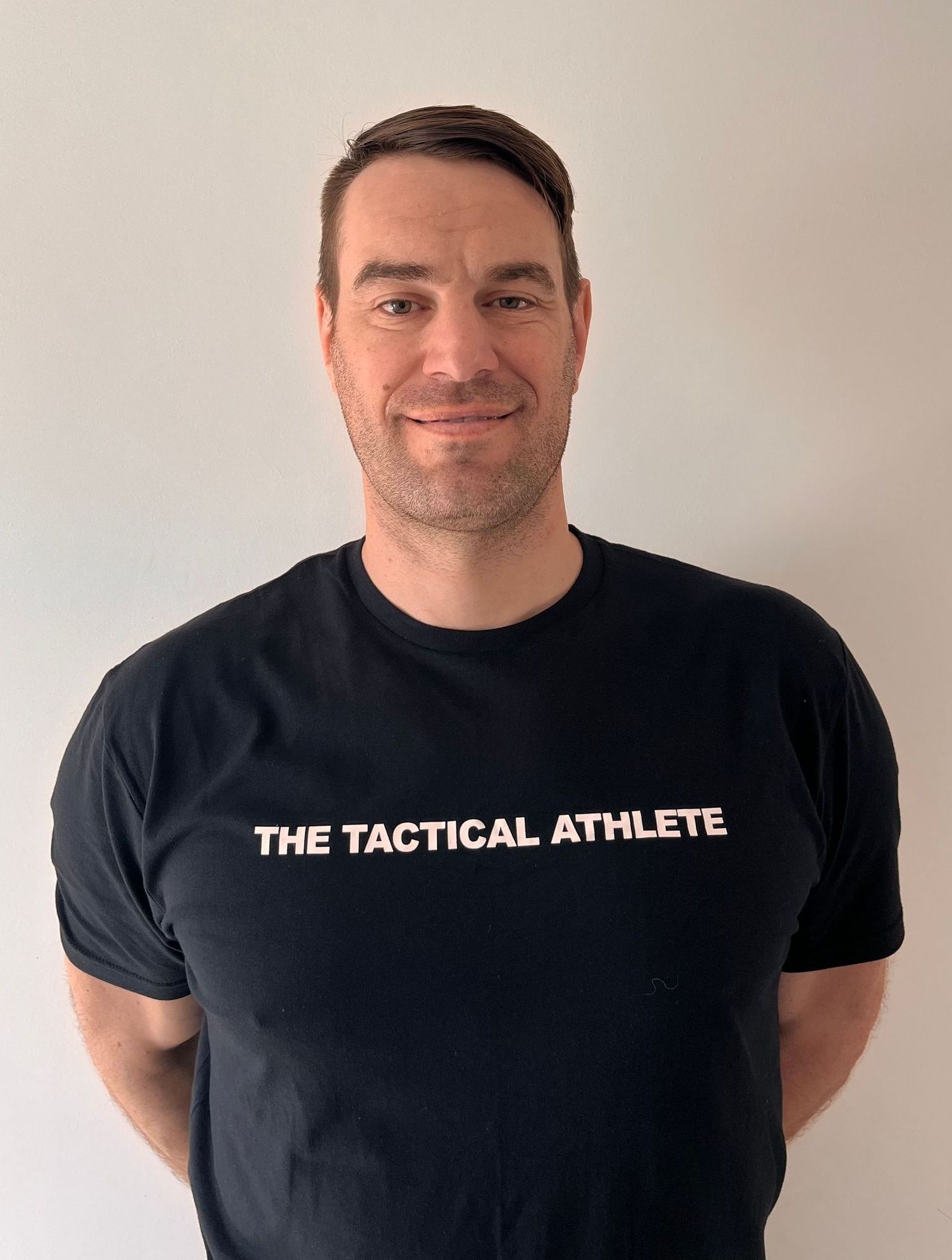 A man wearing a black t-shirt that says the tactical athlete