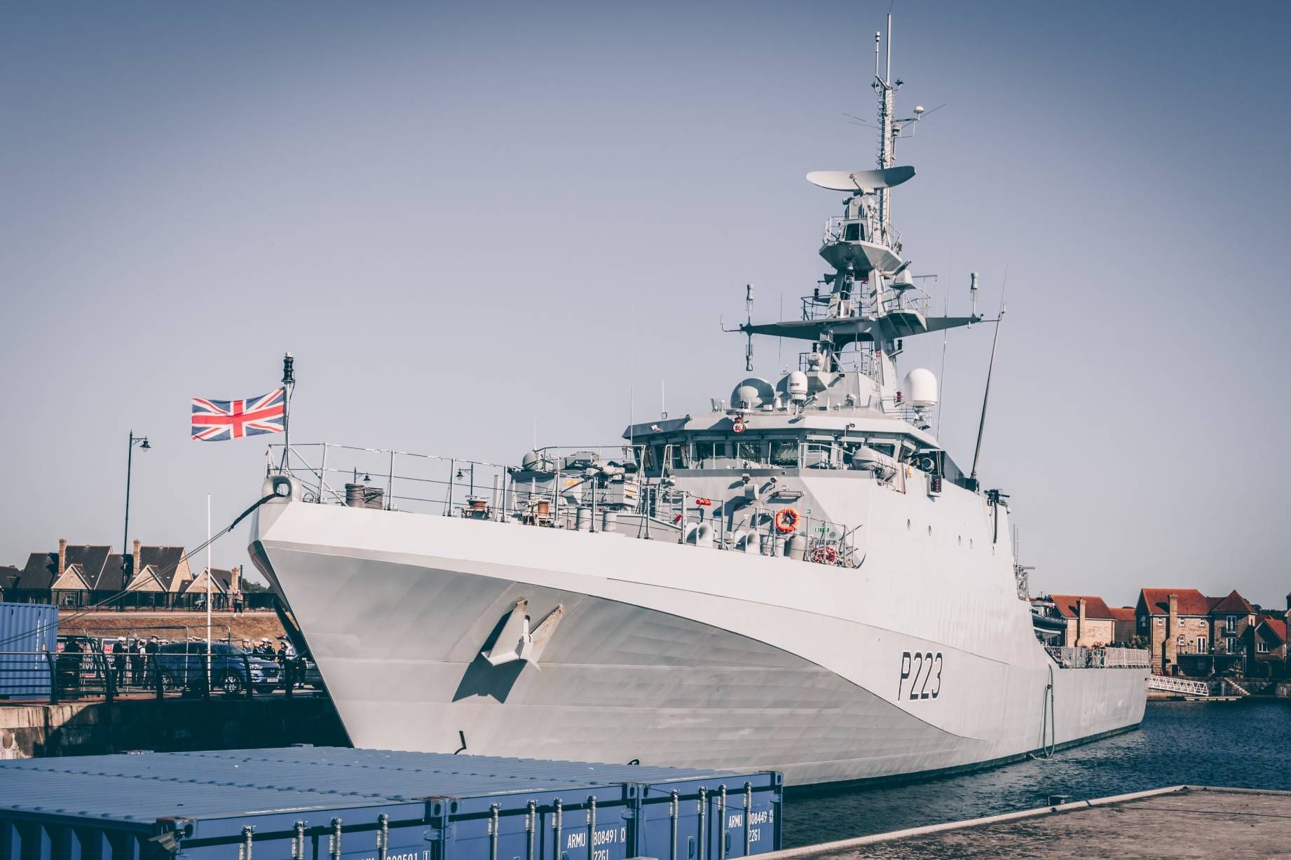 a large military ship is docked in a harbor .