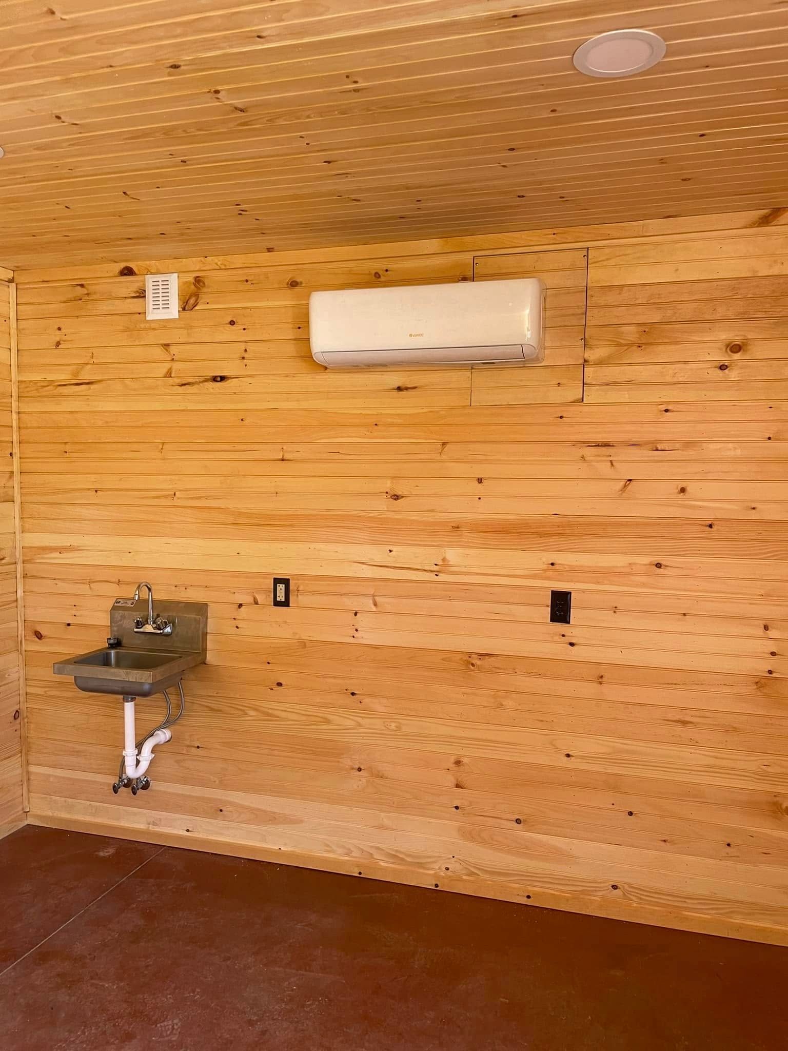A bathroom with a sink and air conditioner on the wall.