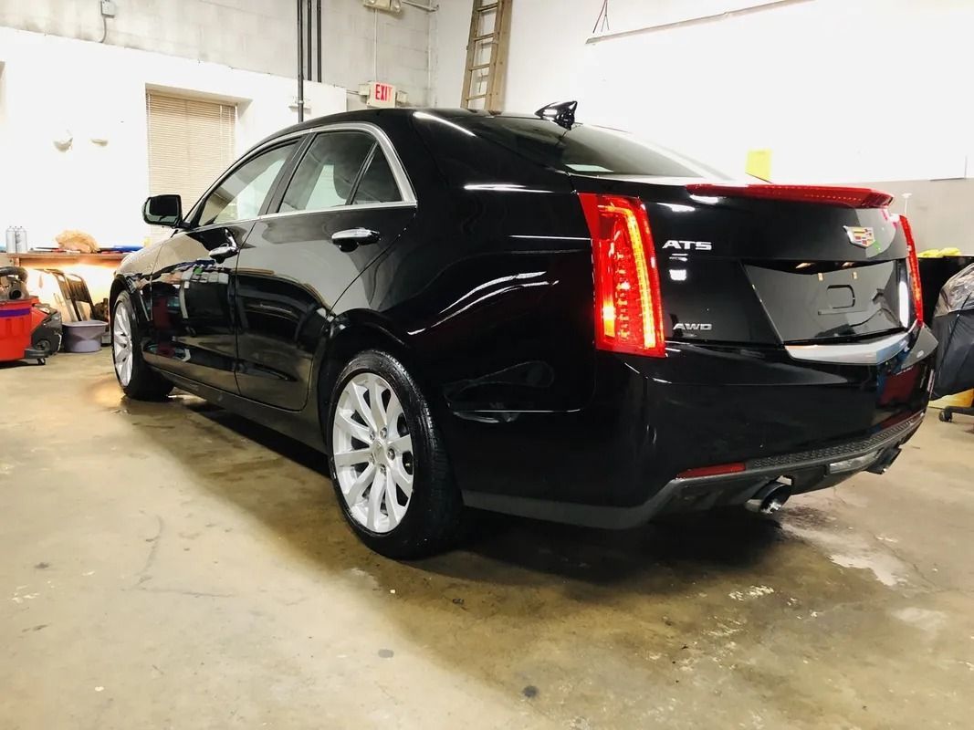 Black Cadillac SUV parked inside a garage, rear view with taillights lit