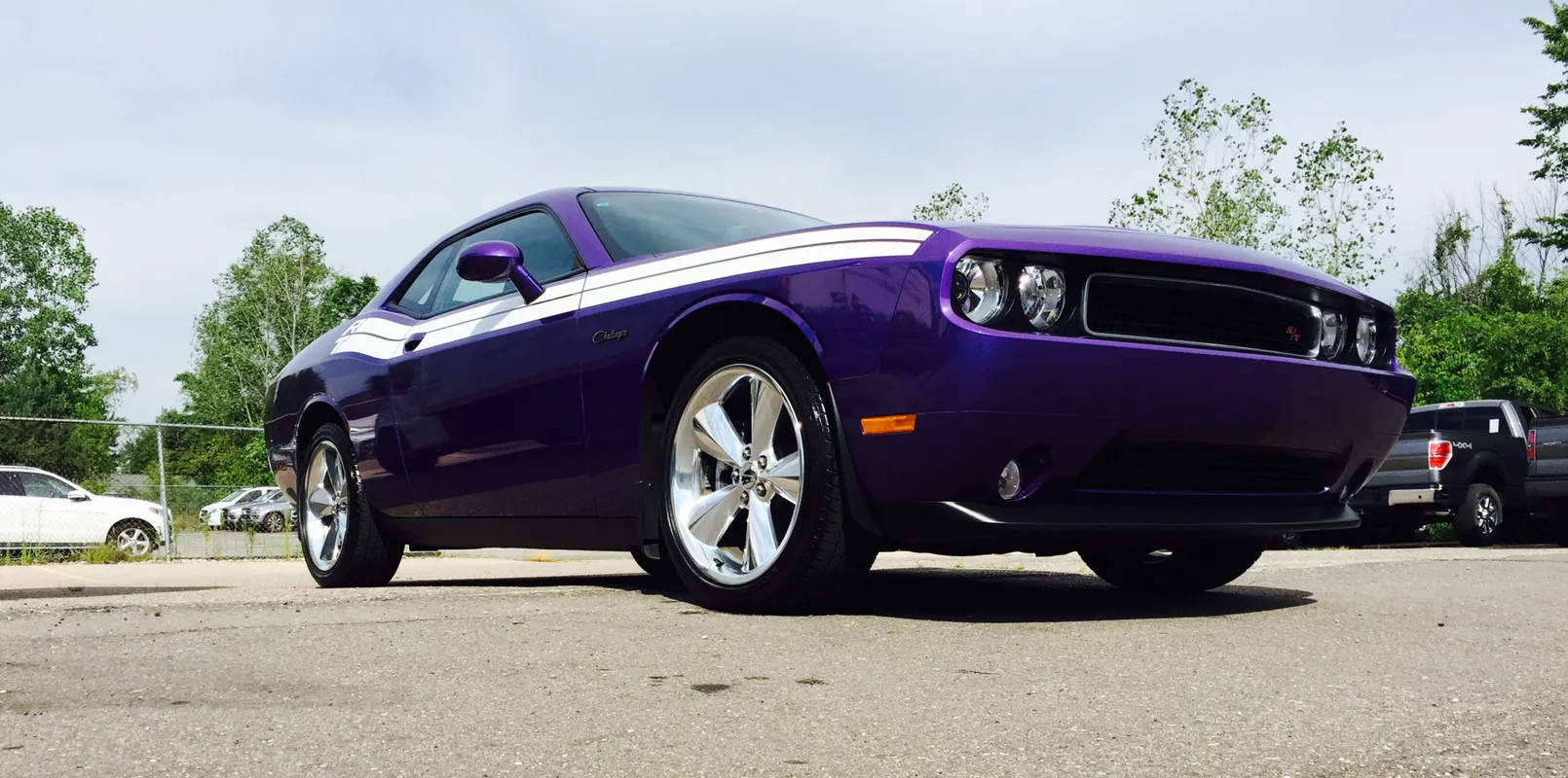 Purple classic muscle car parked outdoors on pavement under a bright sky