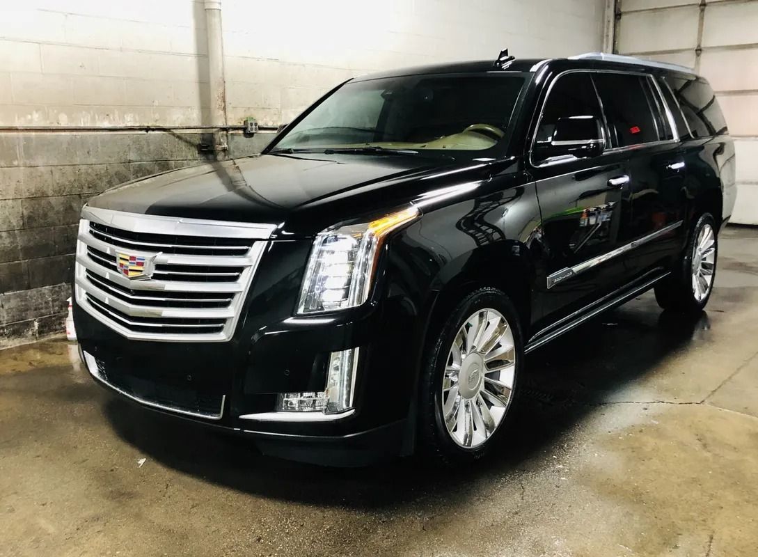 Black Cadillac SUV parked indoors, front view in a concrete garage