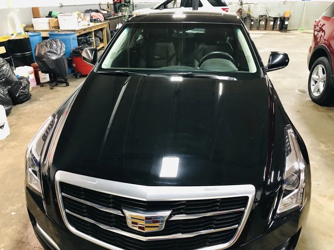 Black Cadillac SUV parked indoors in a garage, front view