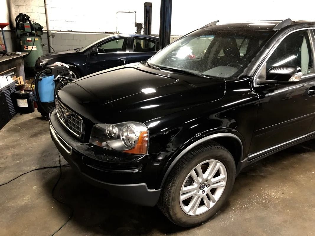 Black SUV parked inside an auto repair shop with tools and equipment in the background