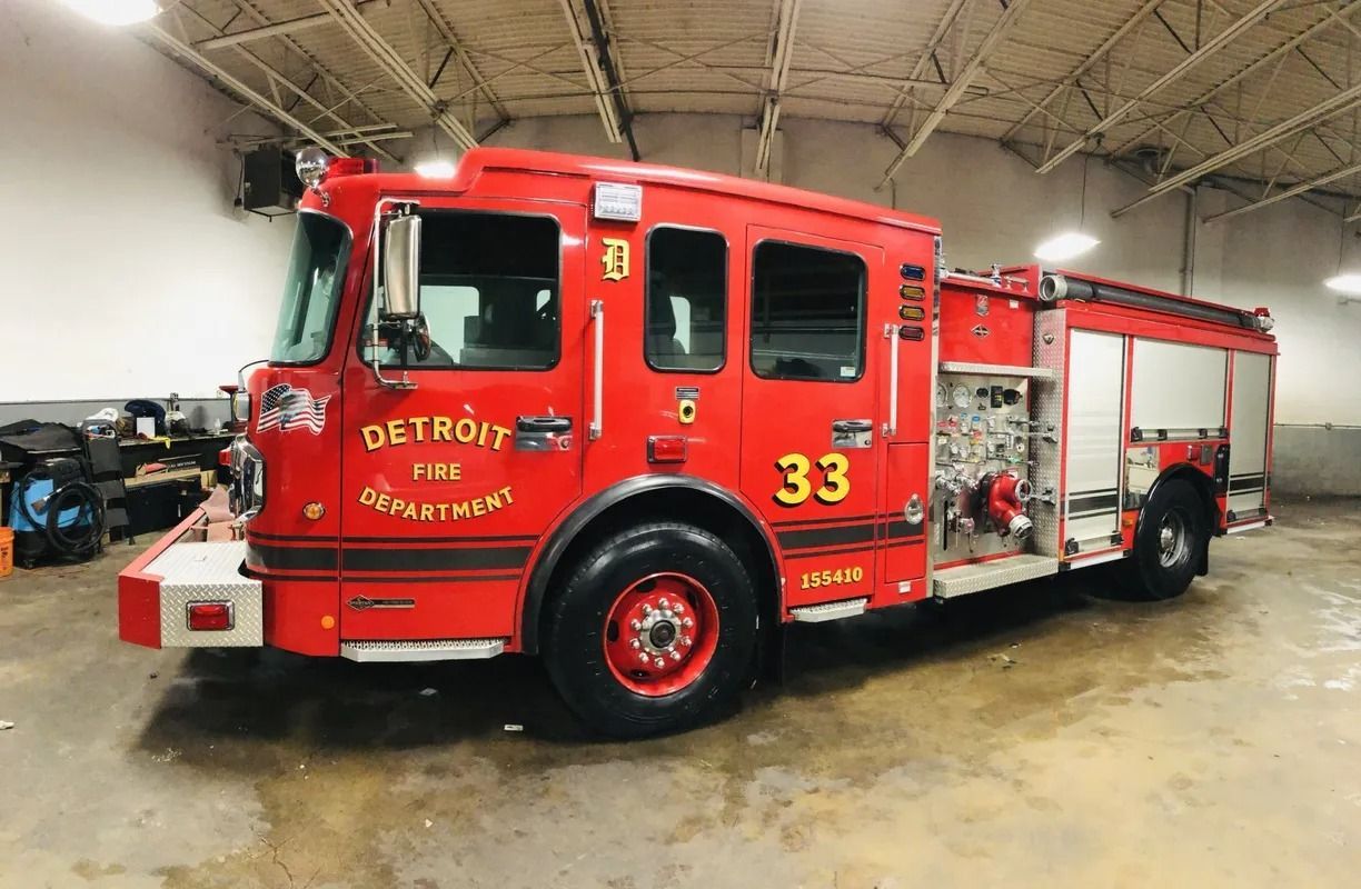 Red Detroit fire truck numbered 33 parked indoors in a garage