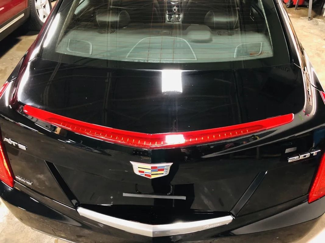 Rear view of a black Cadillac sedan with a red light strip and chrome trim