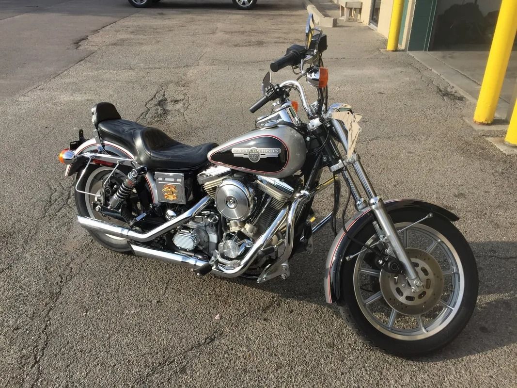 Black cruiser motorcycle parked on asphalt beside yellow bollards