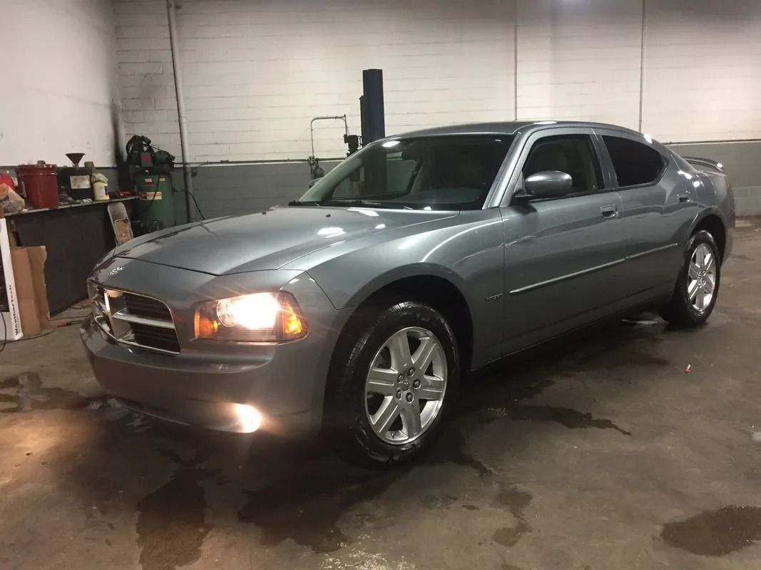 Silver sedan parked in a dim garage with headlights on