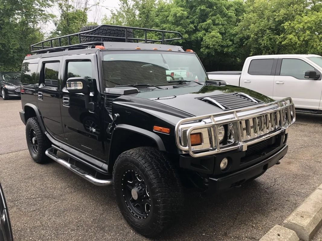 Black Hummer SUV parked outdoors with roof rack and off-road tires