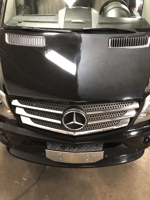 Front view of a black Mercedes-Benz SUV in a garage, with hood and grille visible