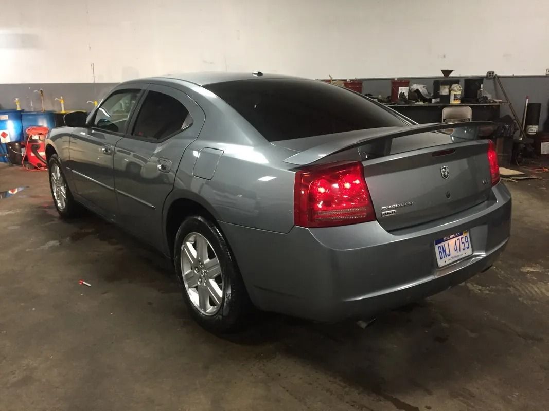 Gray sedan parked in a garage, rear view with red taillights visible.