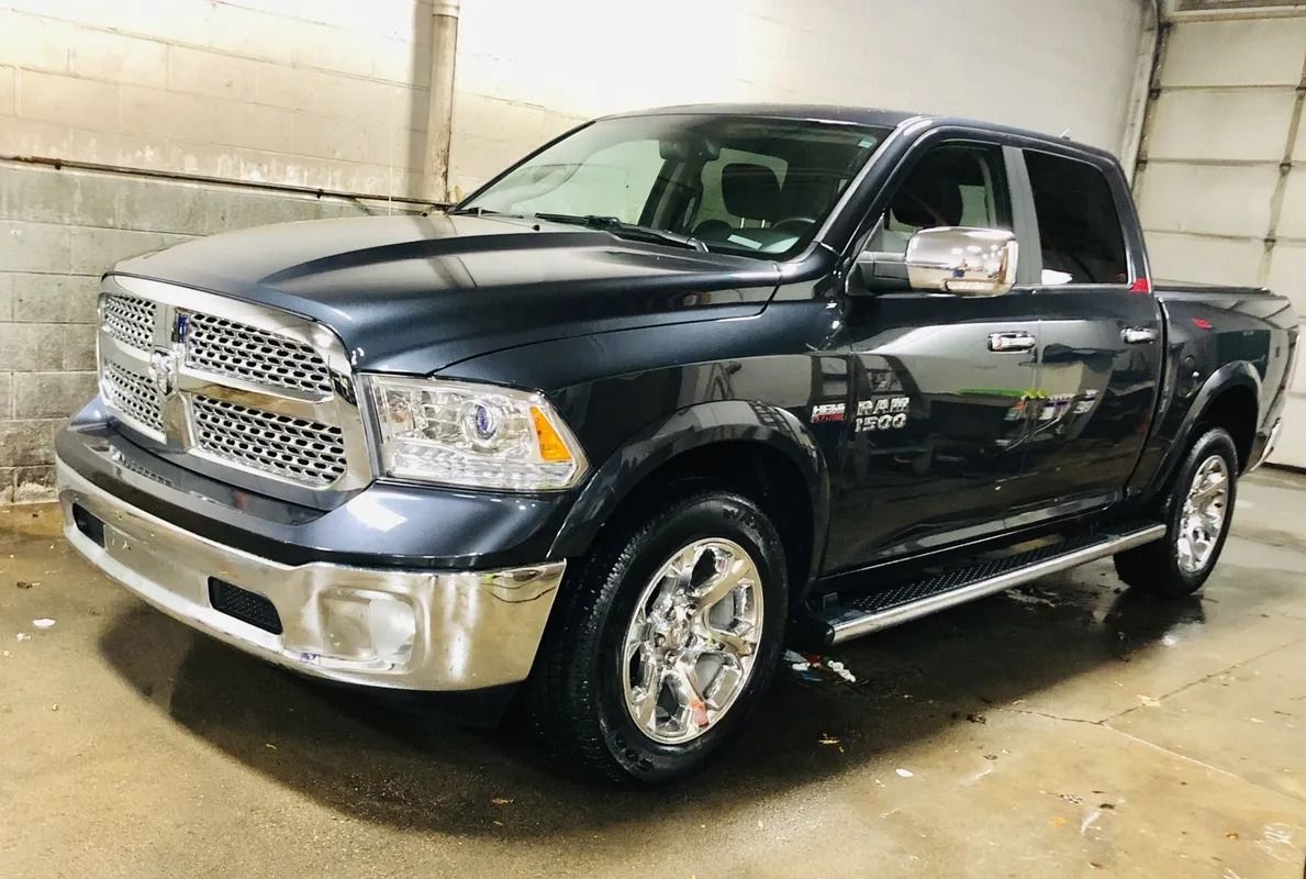 Black Dodge Ram pickup truck parked indoors on a wet concrete floor, front-left view