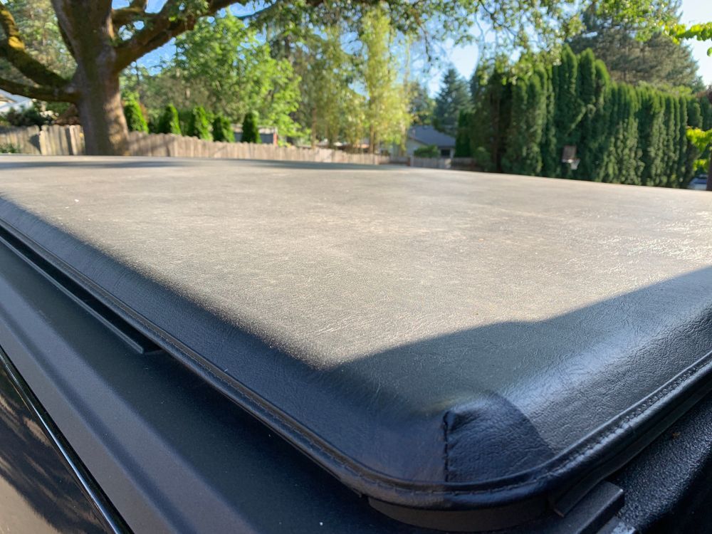 Black hot tub cover on an outdoor spa in a sunny backyard