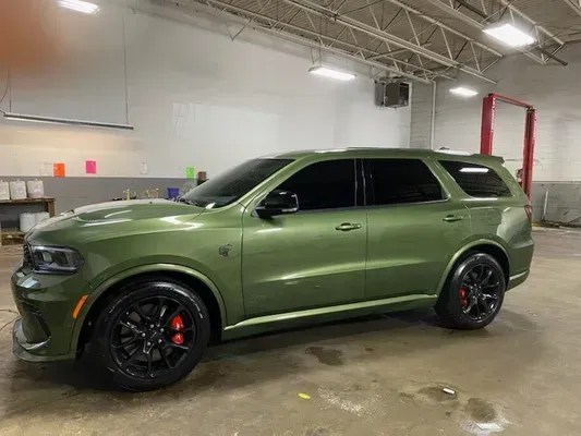 Green SUV with black wheels parked indoors in a garage or warehouse
