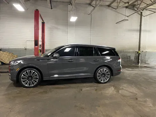 Gray SUV parked inside an industrial garage with red car lifts and concrete floor