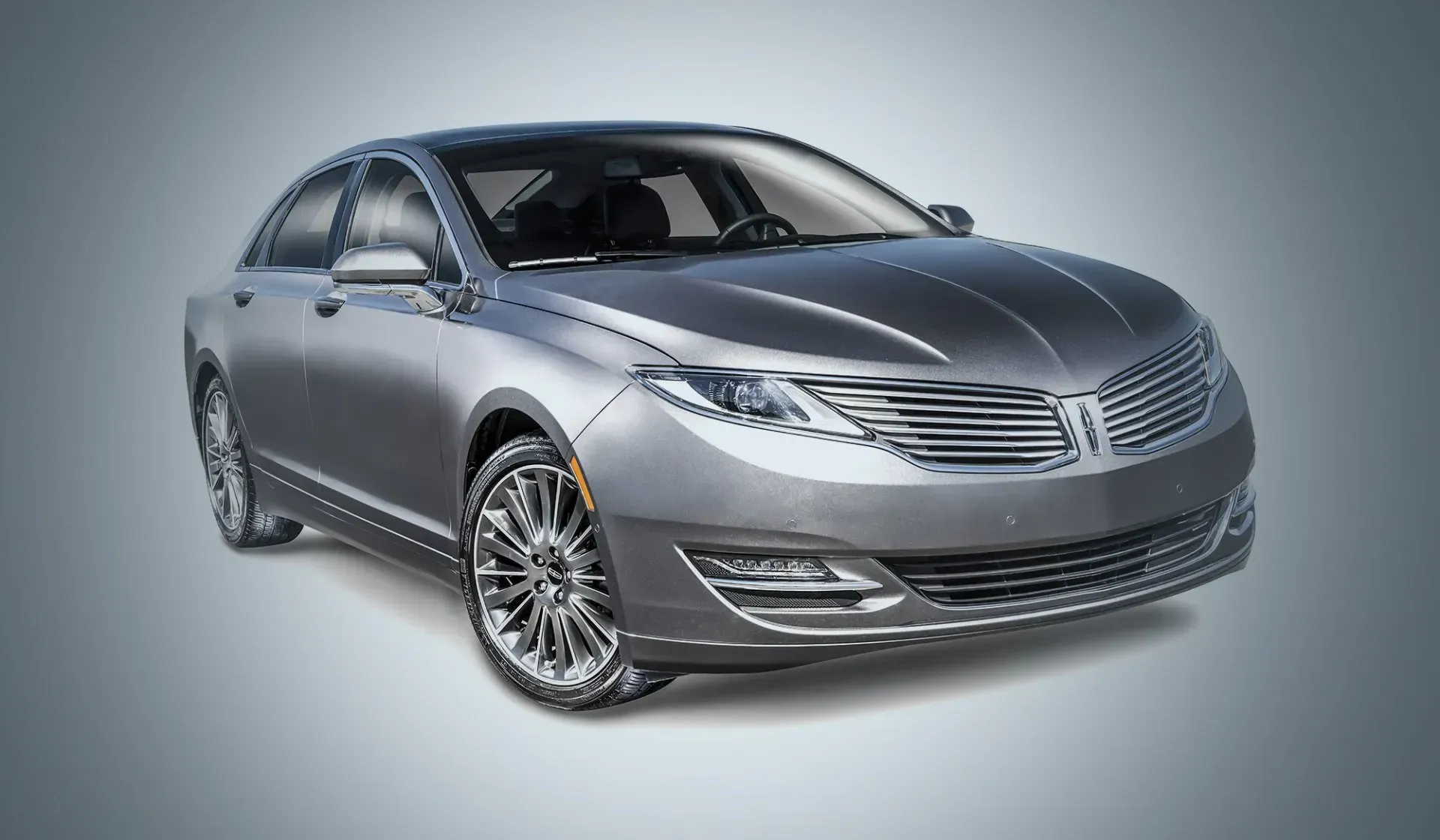 Silver luxury sedan on a light gray background, angled front view