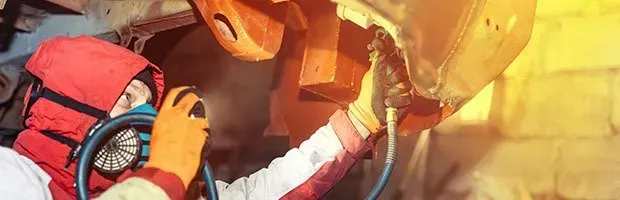 Two firefighters in red gear work with a hose amid bright flames and smoke