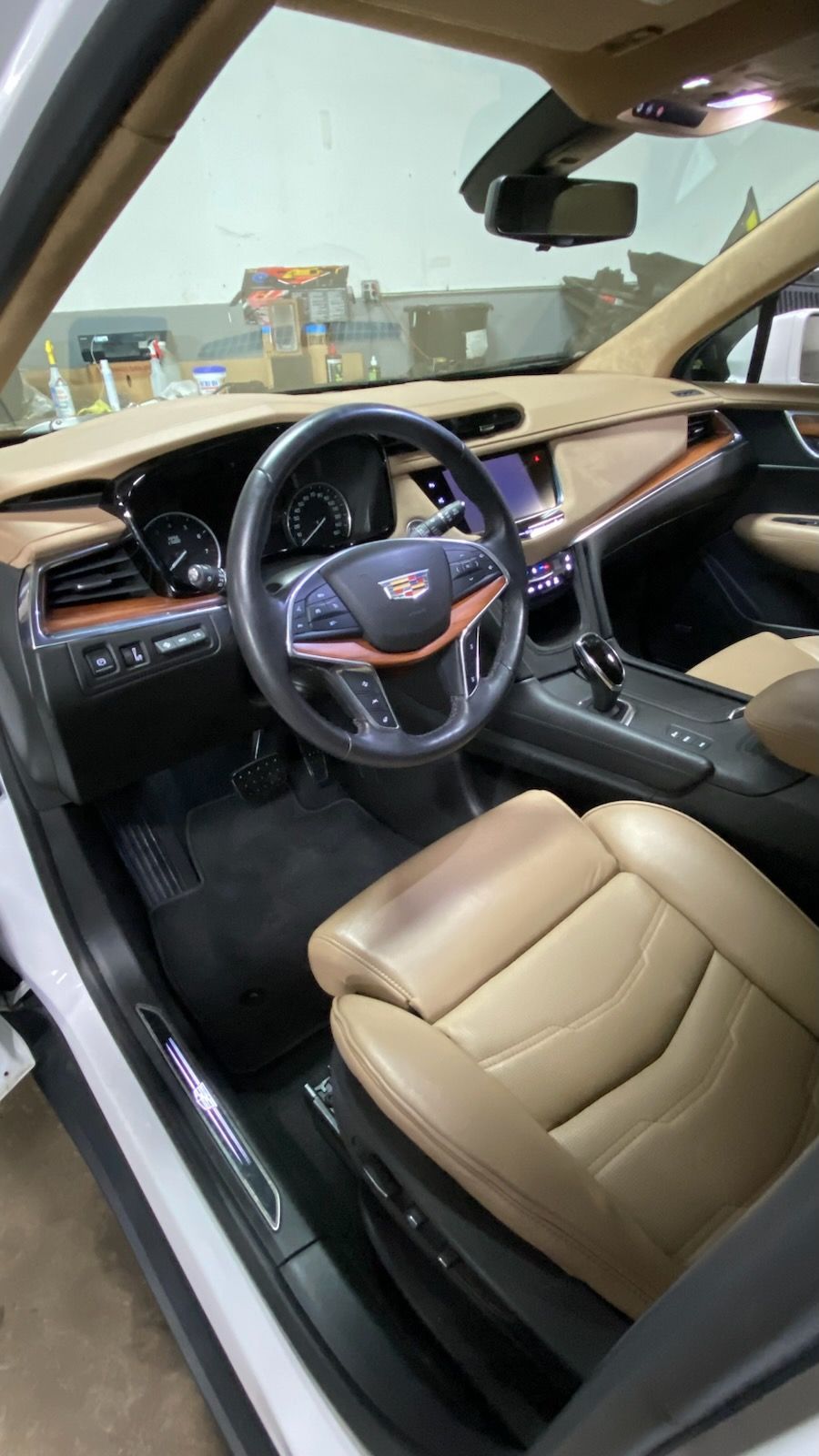 Black-and-tan luxury car interior with leather seats and steering wheel, driver’s door open.