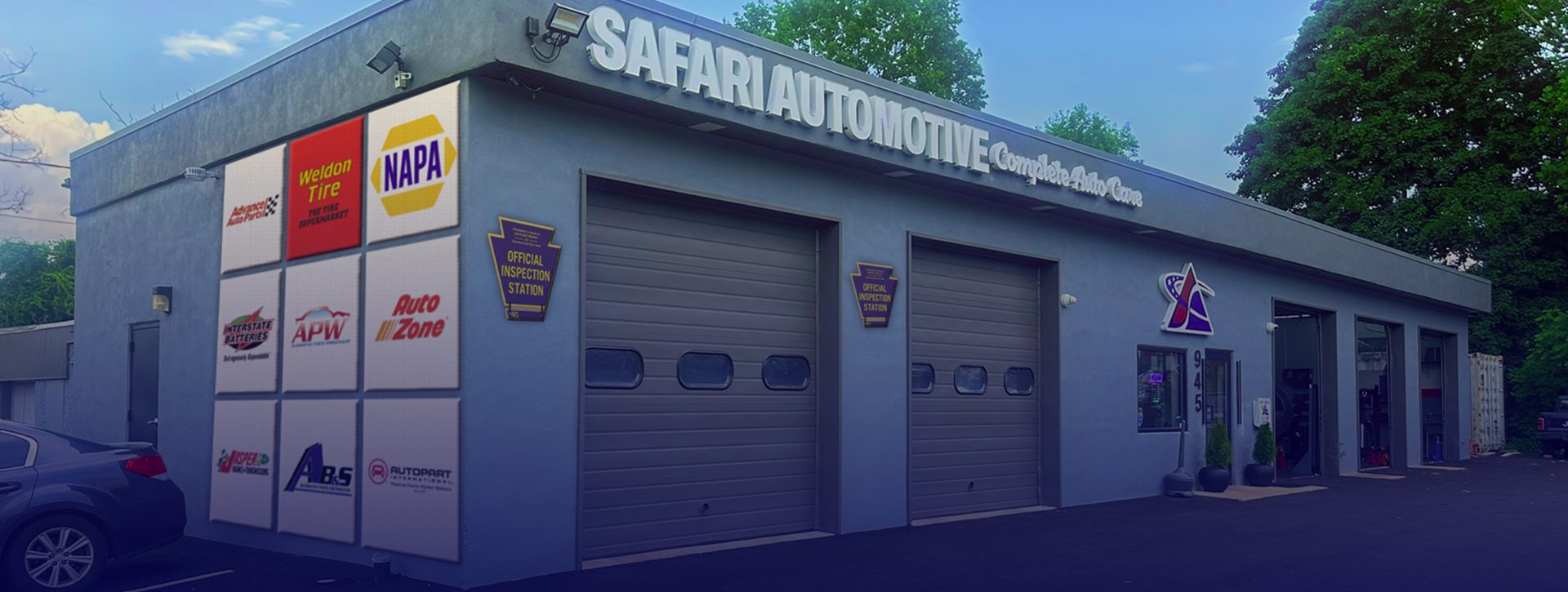 A building with a lot of doors and a yellow van parked in front of it. | Safari Automotive