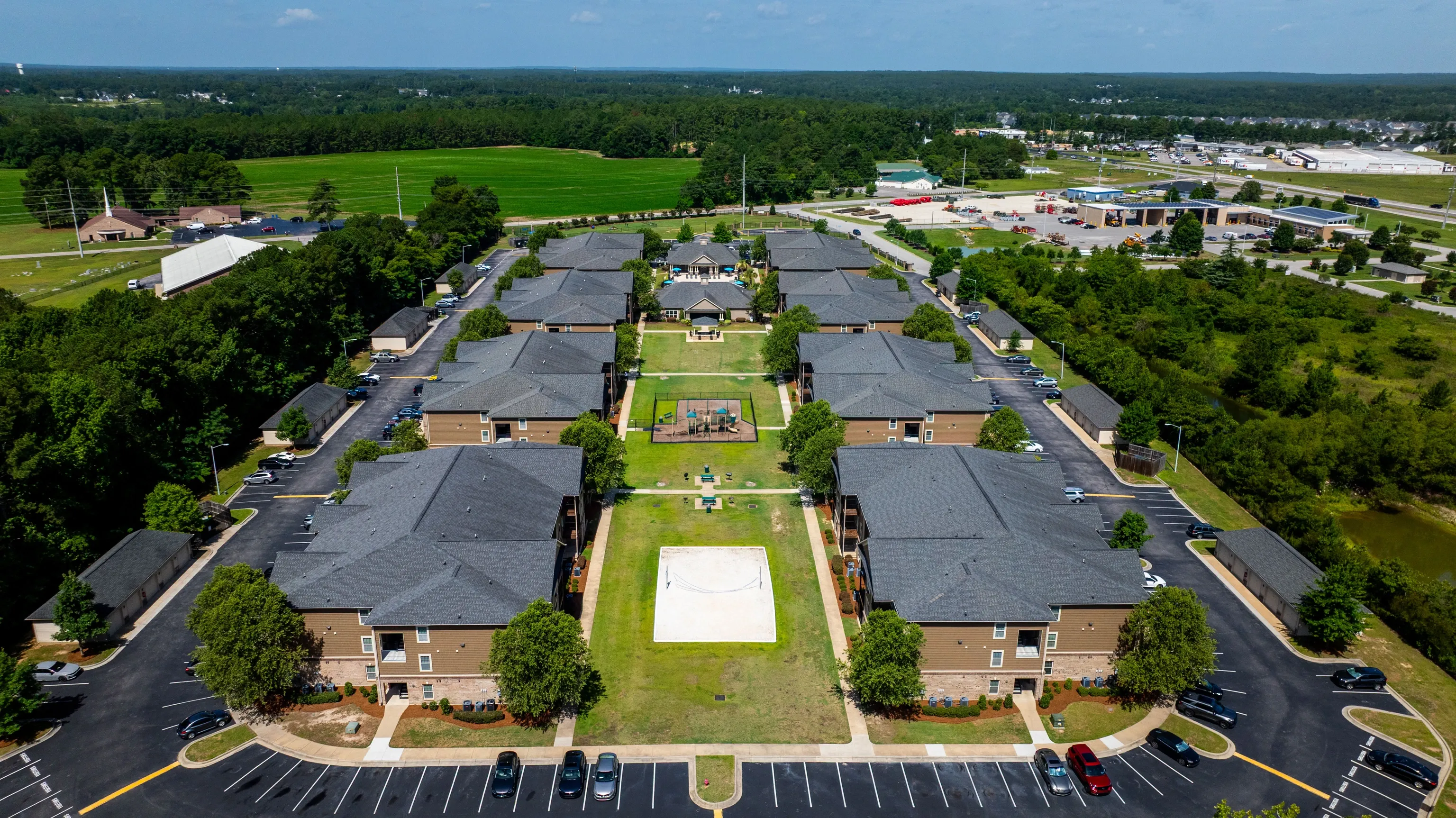 Aerial view of apartment buildings with a central courtyard, playground, and sports court.