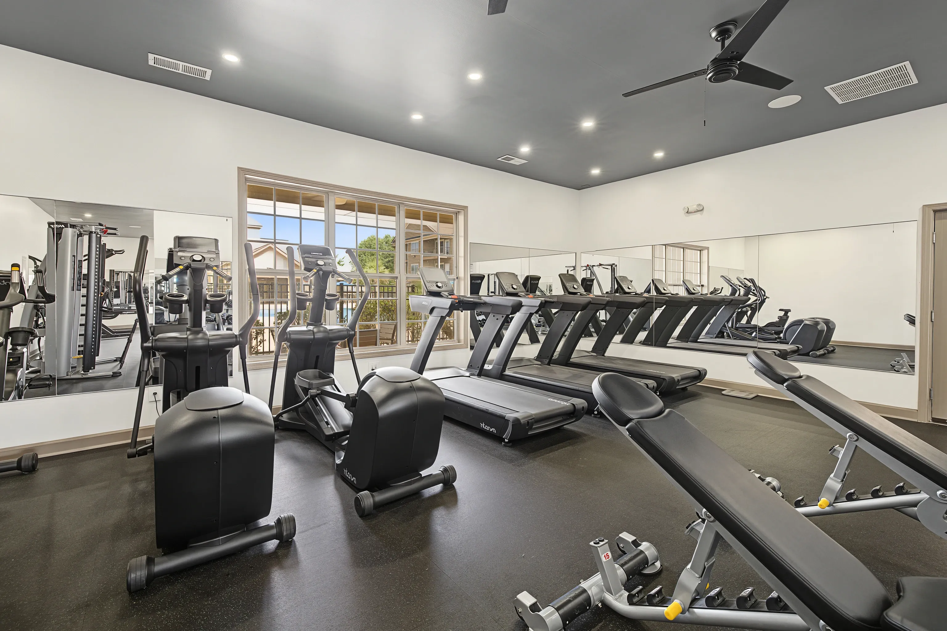 Gym with treadmills, elliptical machines, and weight benches.
