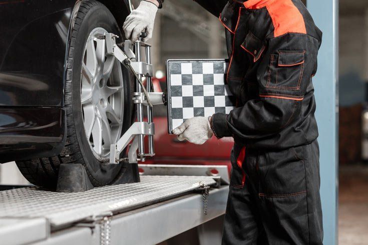 Mechanic Performing Wheel Alignment on a Black Car — Wheel Alignment Centre in Braitling, NT