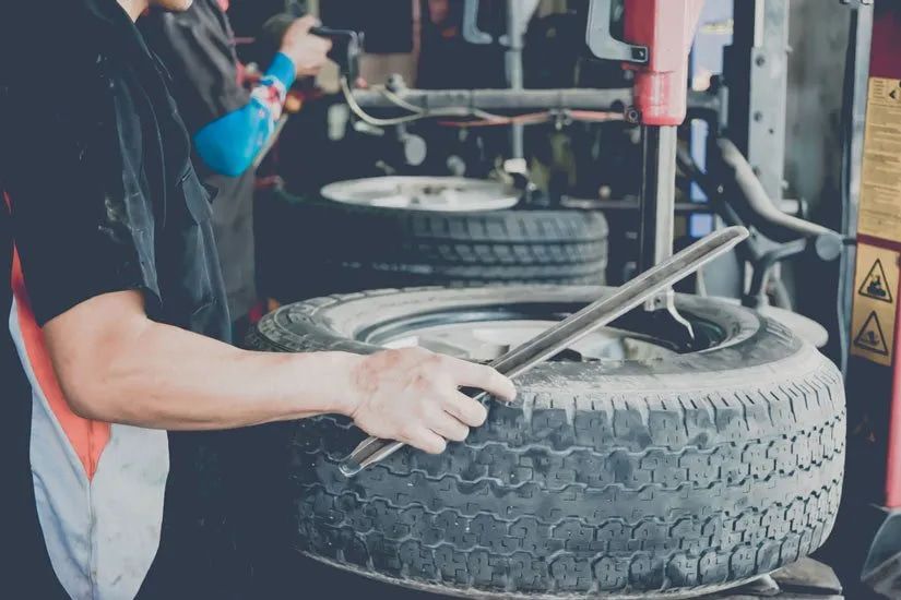 Mechanic Using a Tool to Remove a Tire From a Rim in a Garage — Wheel Alignment Centre in Braitling, NT