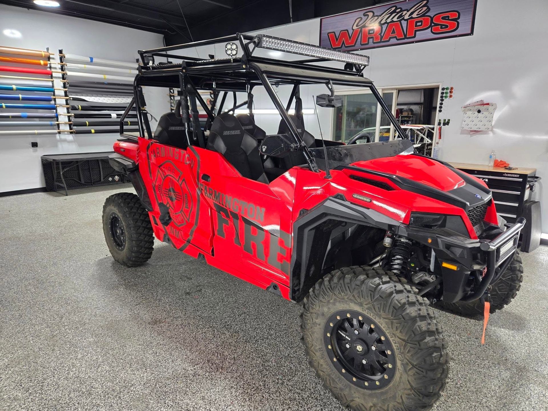 A red atv is parked in a garage next to a sign that says wraps.