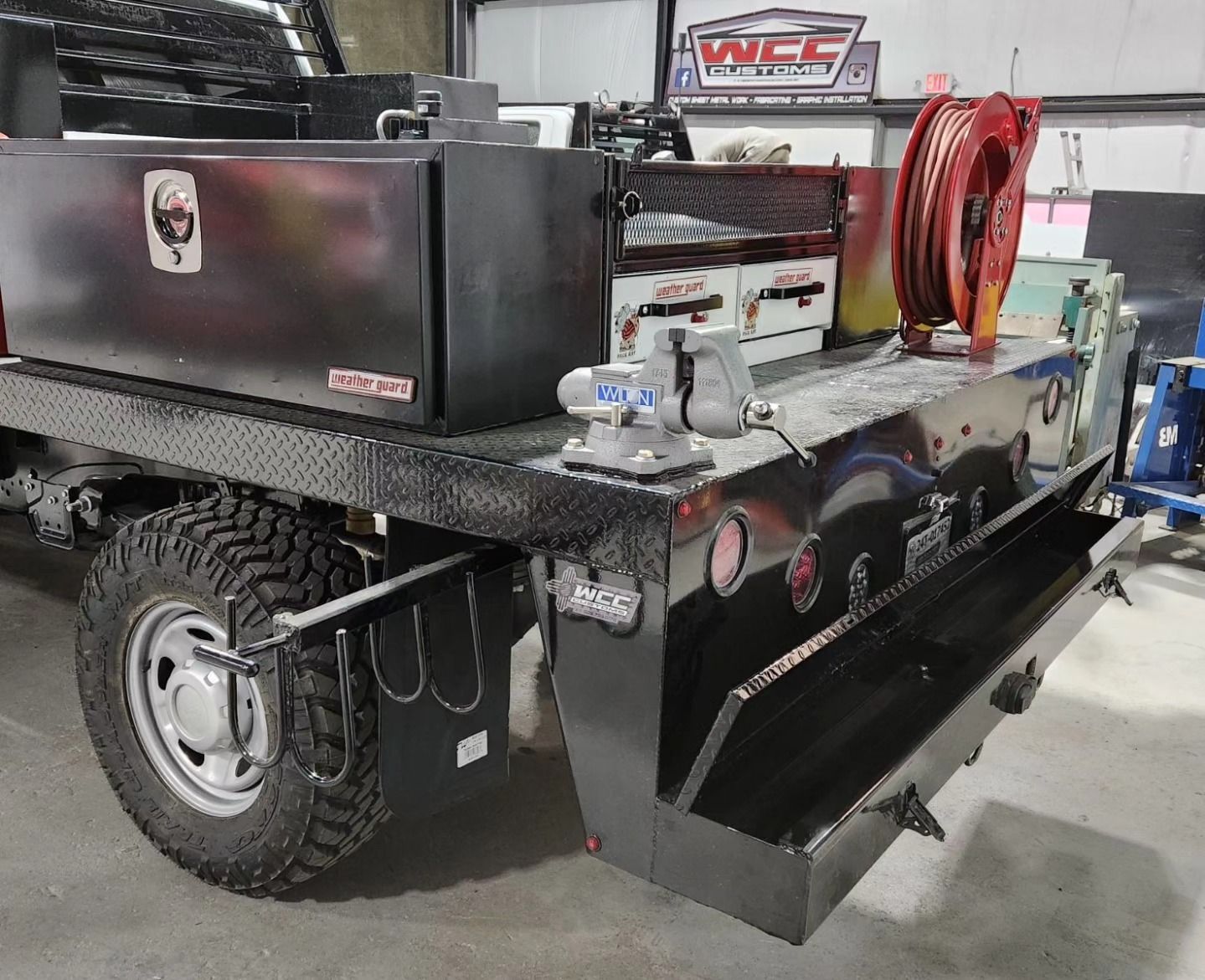 A black truck with a toolbox on the back is parked in a garage. A black truck with a toolbox on the back is parked in a garage.