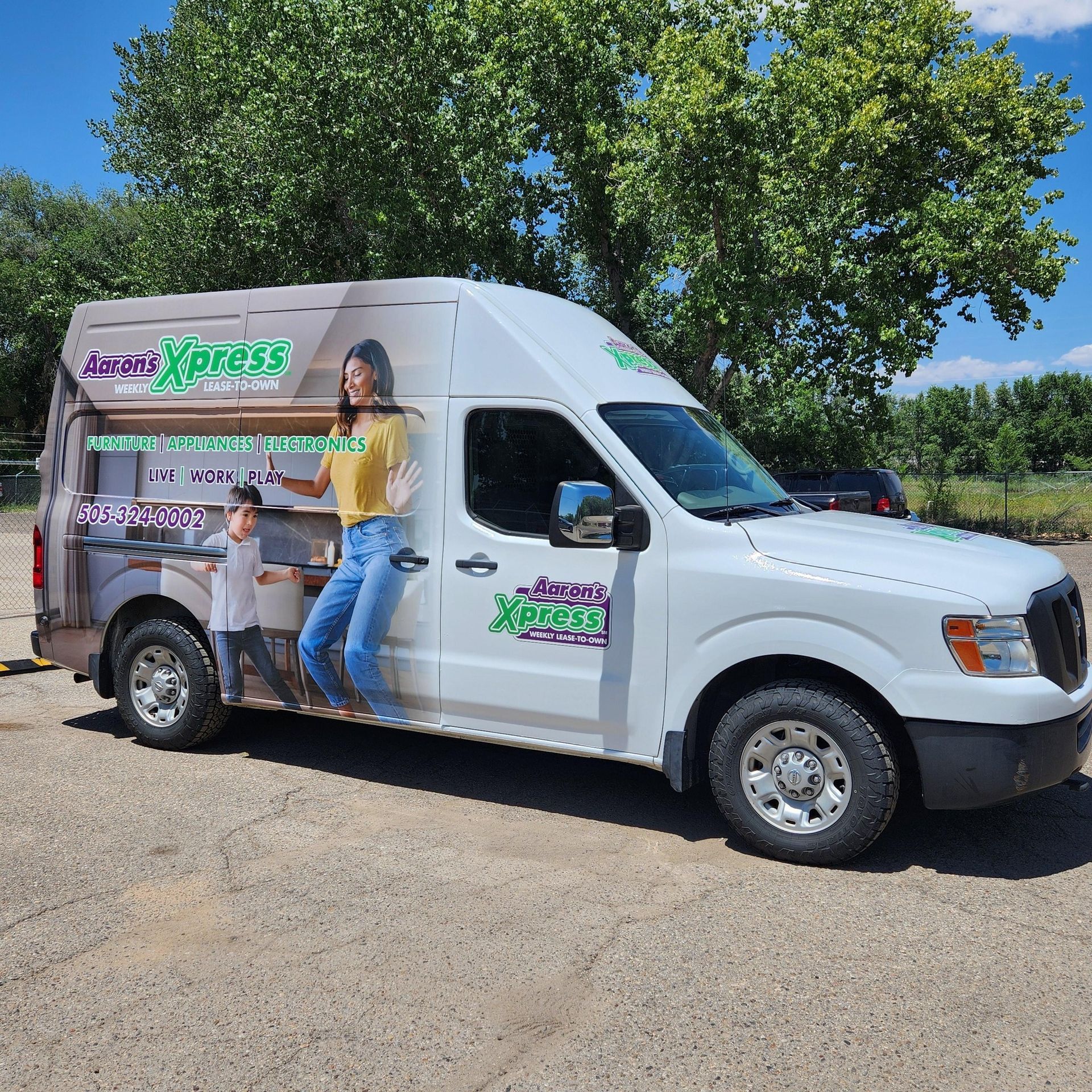 A white van with a picture of a woman and a boy on the side is parked in a parking lot. A white van with a picture of a woman and a boy on the side is parked in a parking lot.
