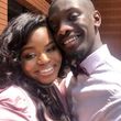 Smiling Black couple embracing outdoors. Woman in pink; man in pink shirt and burgundy bow tie.