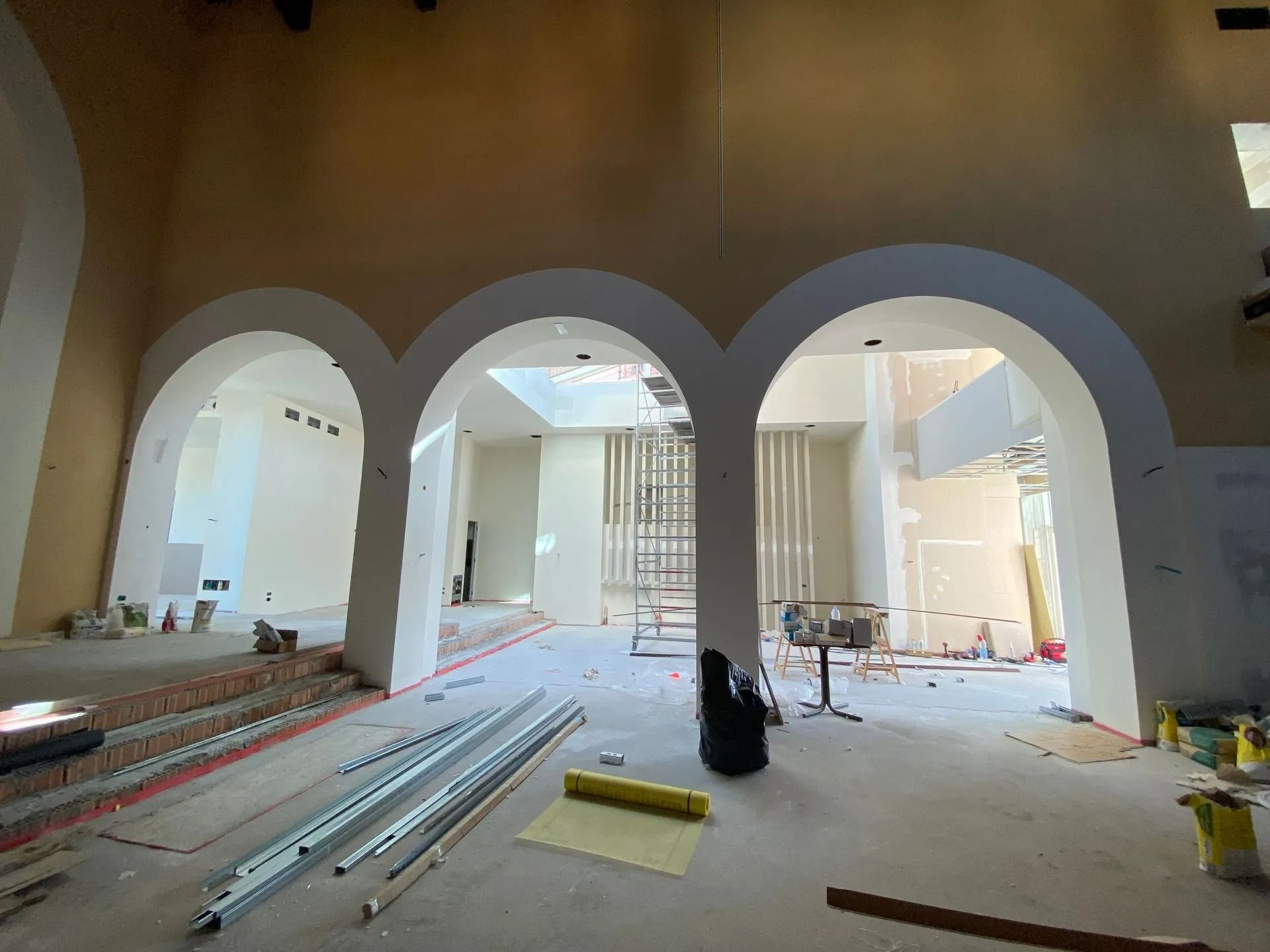 Vista interna di un edificio in costruzione, con arcate, muri non finiti e materiali da costruzione.