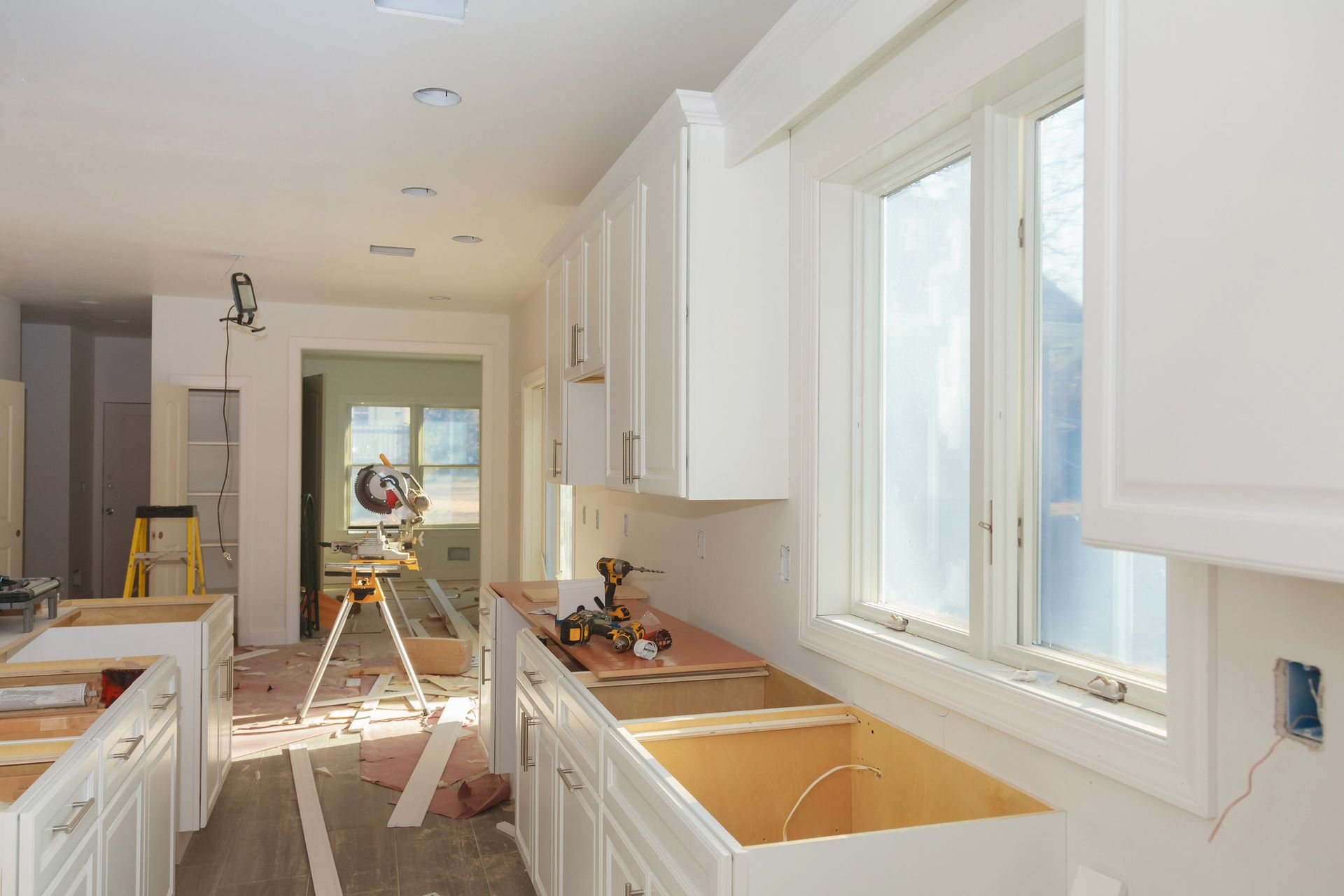 A kitchen under construction with white cabinets and a sink.