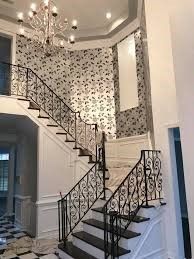 A staircase in a house with a wrought iron railing and a chandelier.
