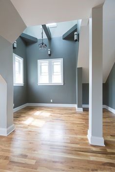 An empty room with hardwood floors and gray walls.