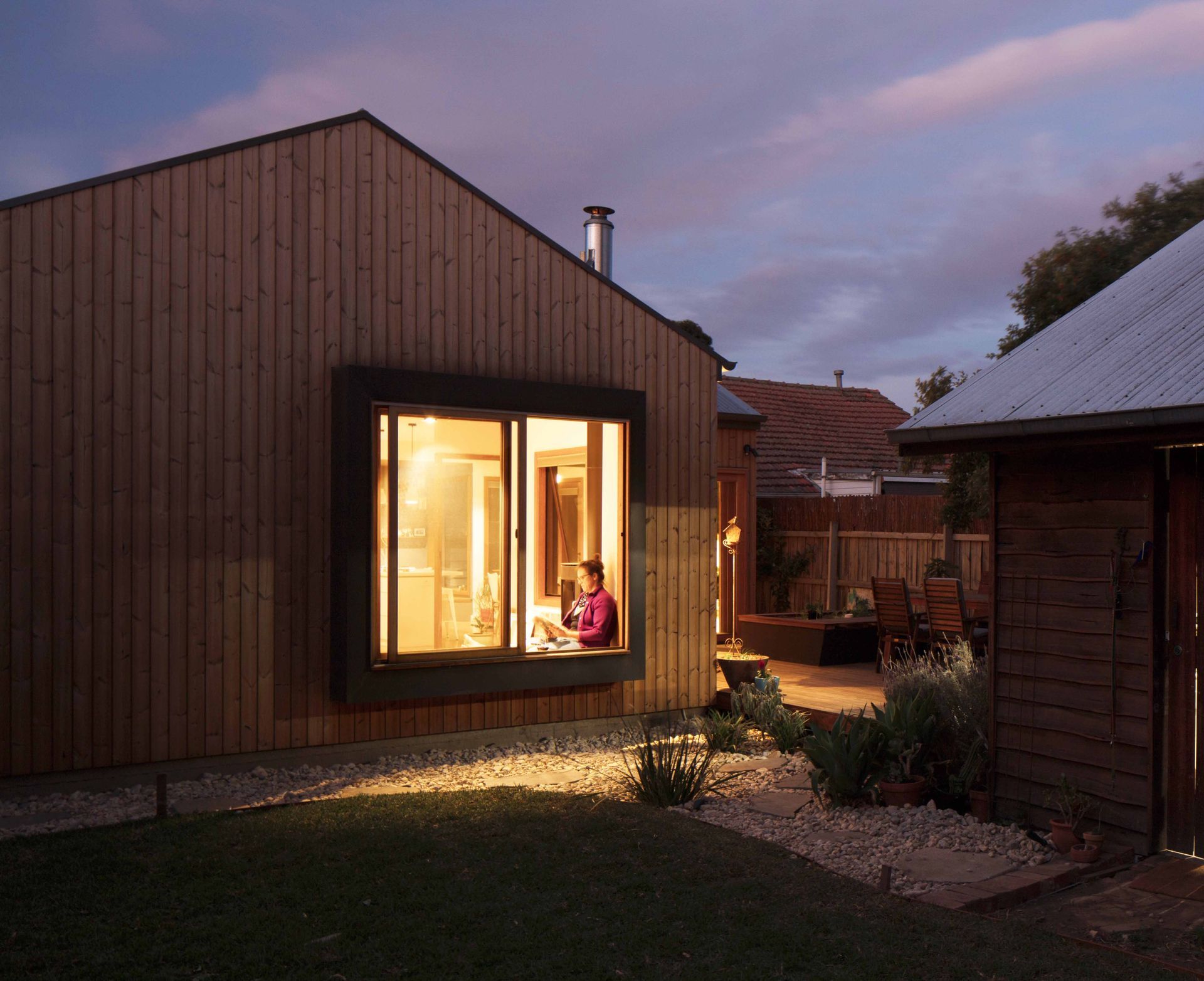 A woman sits in a window of a house at night