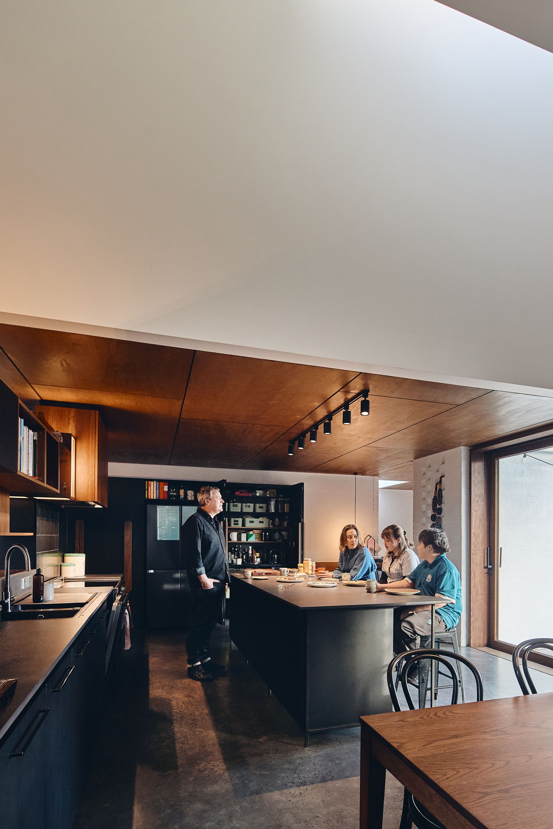 A group of people are sitting at tables in a kitchen.