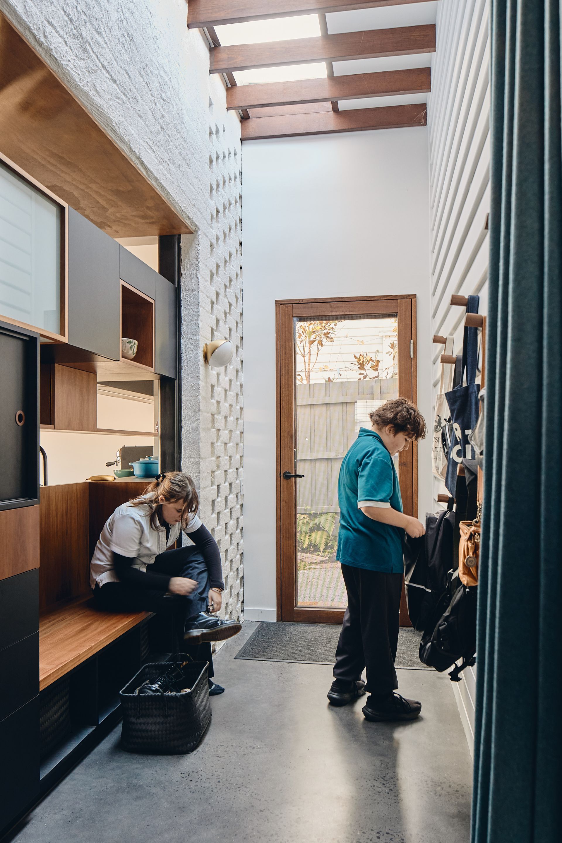 A man is standing in a hallway next to a woman sitting on a bench.