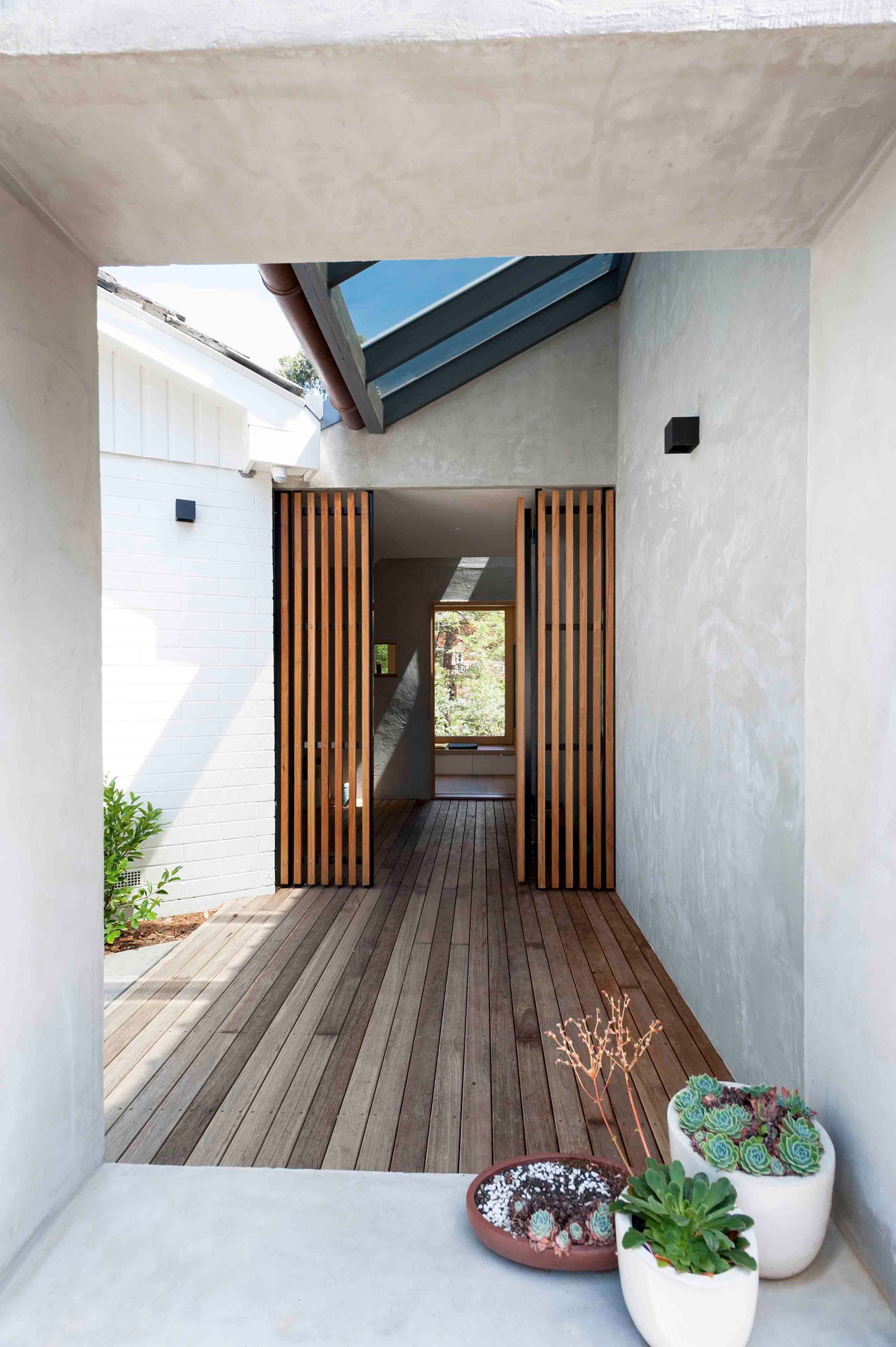 A hallway with a wooden floor and potted plants.