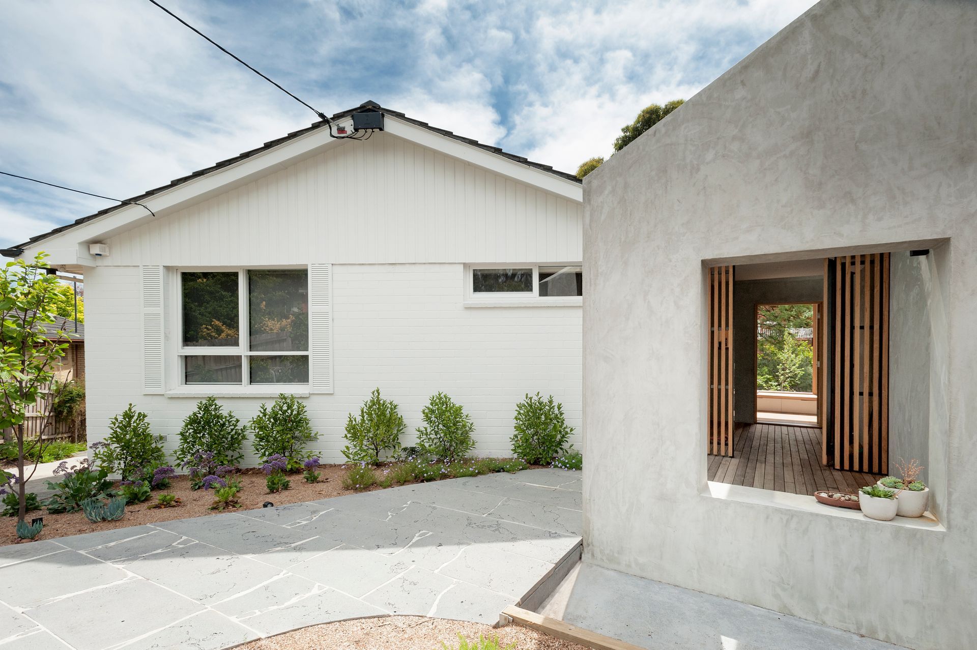 A white house with a concrete wall and a window.