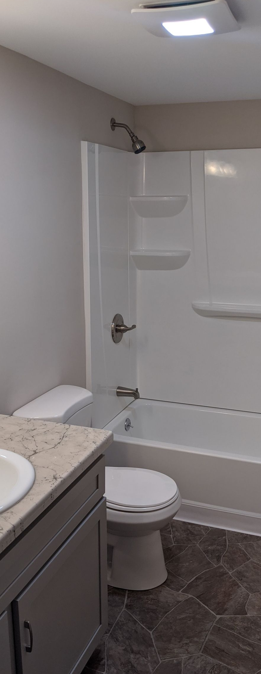 Small bathroom with a tub-shower, toilet, vanity, and white walls.