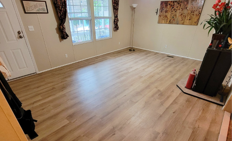 Empty living room with light wood floors, beige walls, and a windowed door.