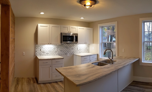 Bright modern kitchen with white cabinets, subway tile backsplash, island, and pendant lighting