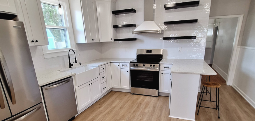 Bright modern kitchen with white cabinets, black stove, stainless dishwasher, and wood-look floor.