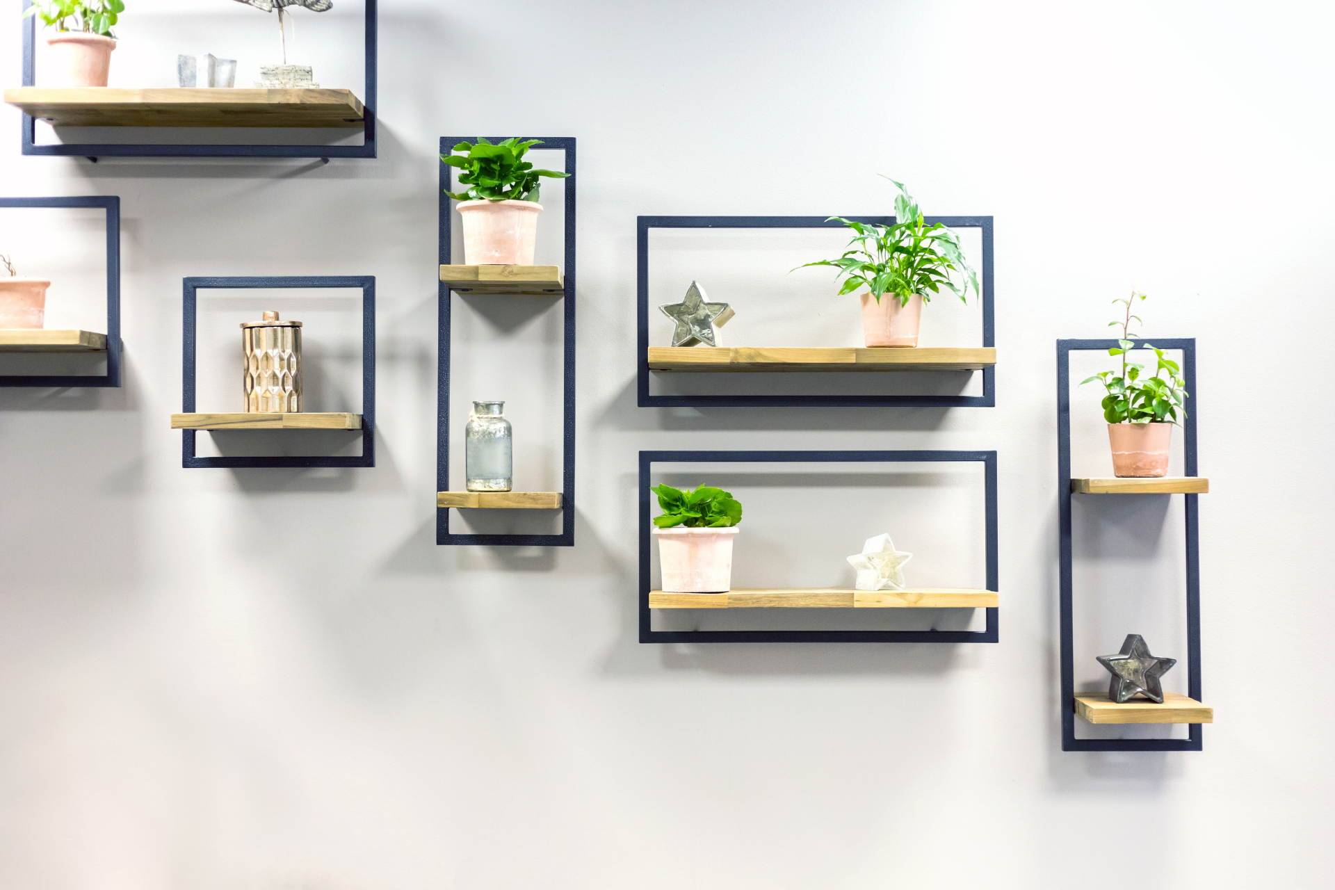 Minimalist wall shelves with small potted plants and decor on a white wall