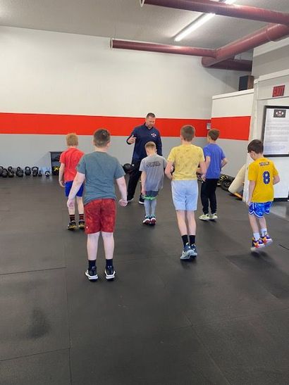Group of kids doing exercises with an instructor in a gym.