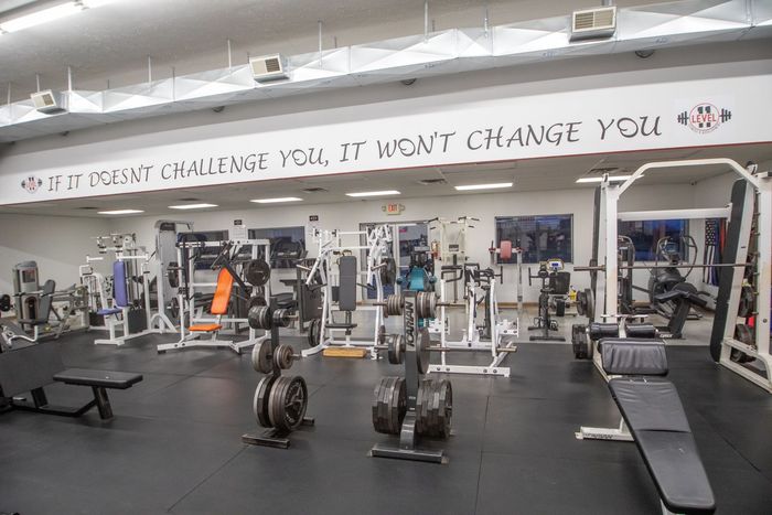 Gym interior with weightlifting equipment. Black floor, white walls with motivational quote.