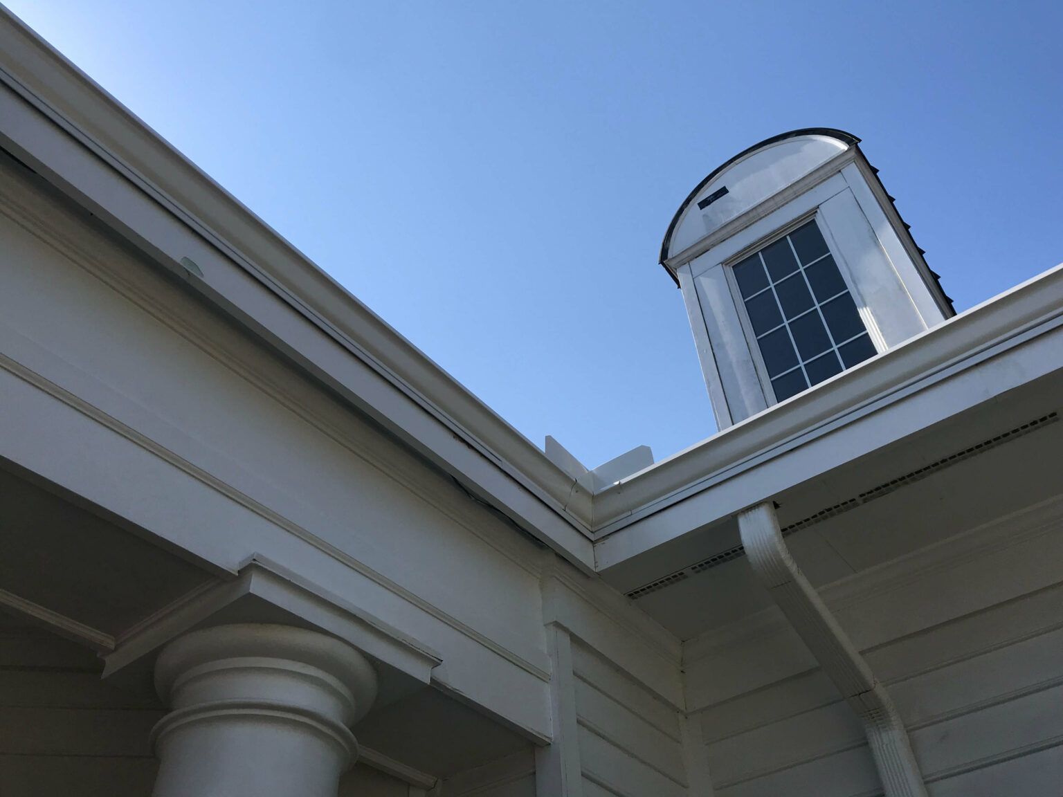 A roof with a green gutter and trees in the background
