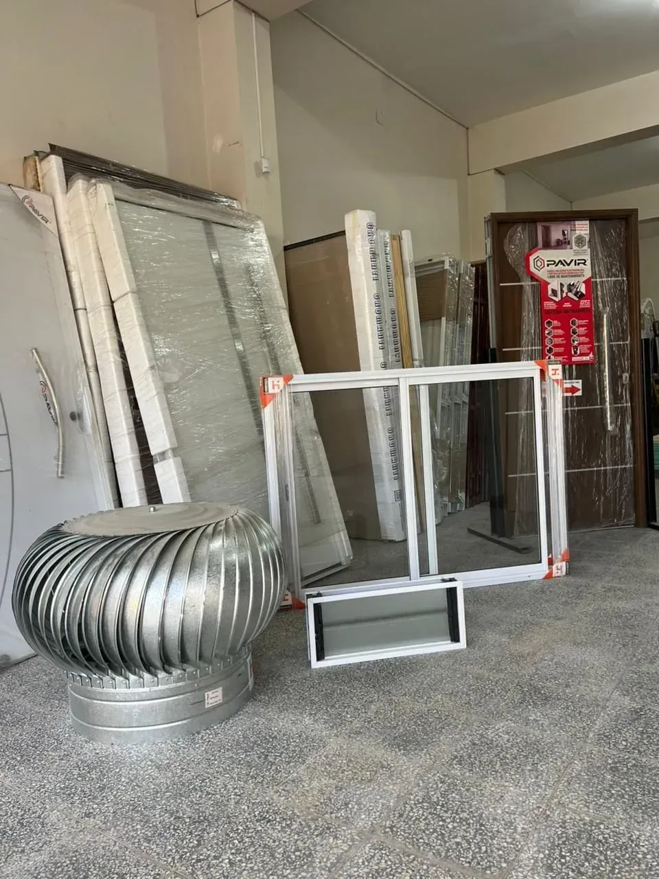 Diversos marcos de ventilación metálicos y piezas de conductos apoyados contra una pared en un taller