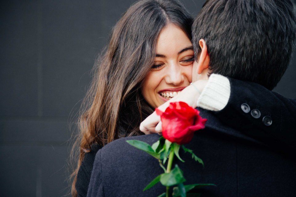 Ragazza con rosa rossa in mano che abbraccia il fidanzato
